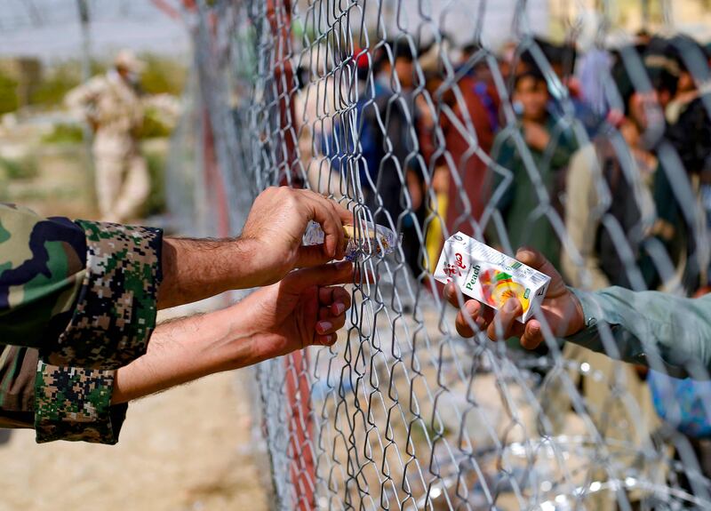 An Iranian soldier distributes boxes of juice to Afghan refugees gathered at the Iran-Afghanistan border between Afghanistan and the southeastern Iranian Sistan and Baluchestan province. AFP