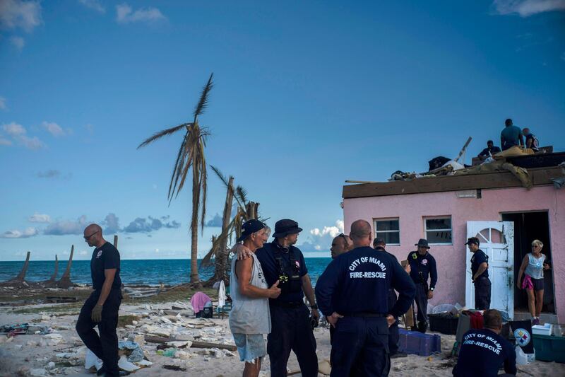 Randy Nagy, center, talks with firefighters arriving from the city of Miami to help those affected by Hurricane Dorian while his wife Silvia, 63, goes out the door of his destroyed house in Pelican Point, Grand Bahama, Bahamas, Monday, Sept. 9, 2019. The American couple retired to Pelican Point, Bahamas 3 years ago, had been traveling to the Bahamas for years and had lived through several storms, including Hurricane Francis. They never imagined that their lives 'work would be destroyed in an instant with the passing of Hurricane Dorian. (AP Photo / Ramon Espinosa)