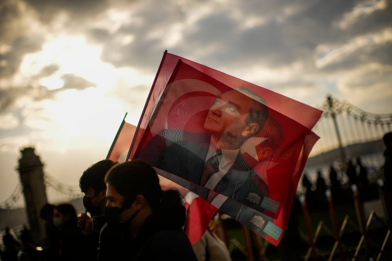 People hold Turkish flags as they pay tribute to Turkey's founding father Mustafa Kemal Ataturk, at Dolmabahce palace in Istanbul, Turkey, on November 10, 2021. AP