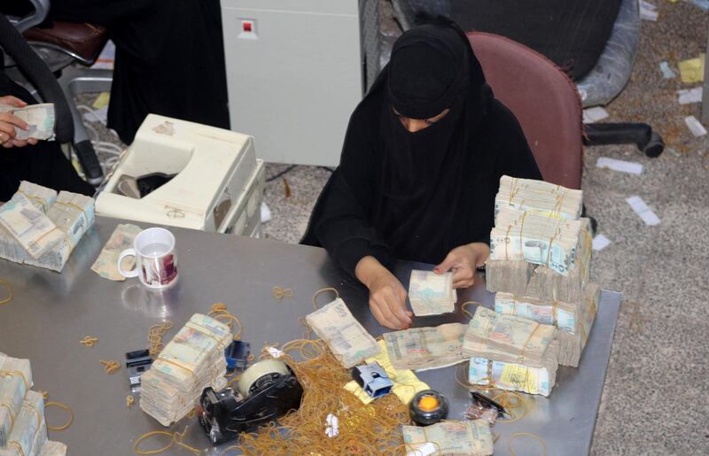 A bank teller counts money at the Central Bank of Aden in Aden on December 13, 2018. Yemen, the Arab world's poorest country is crippled by a humanitarian crisis, with images of skeletal children in famine-like conditions grabbing global attention, but economic dysfunction appears to be at the heart of the problem. / AFP / Saleh Al-OBEIDI
