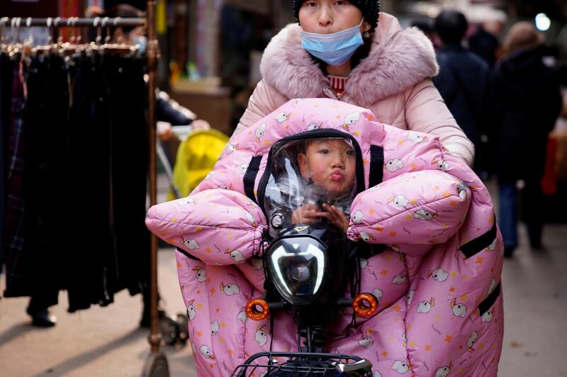 A woman wearing a face mask rides a bicycle with a child, following an outbreak of the coronavirus disease in Wuhan, Hubei province, China. Reuters