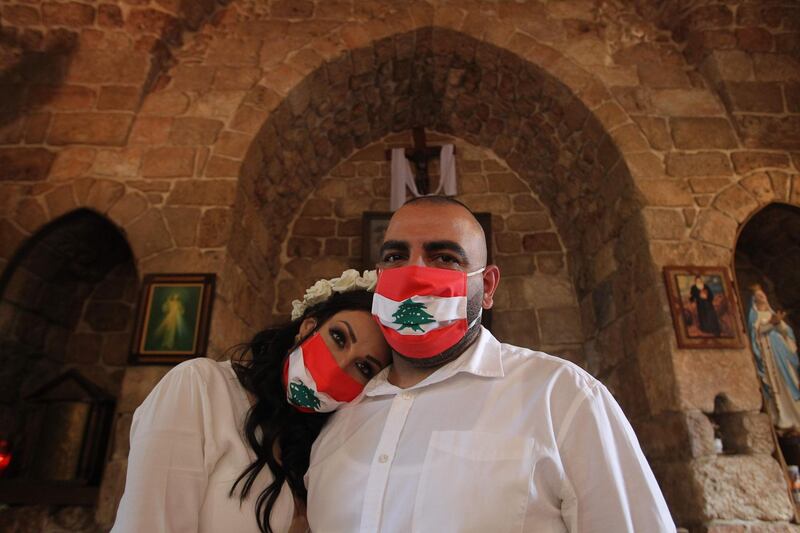 Lebanese bride and groom Joanna and Marc wearing protective masks designed as a national flag, pose for pictures during their wedding cermony attended only by close relatives amid the COVID-19 pandemic, at the Saint Georges church in the Hadath region, east of the capital Beirut.   AFP