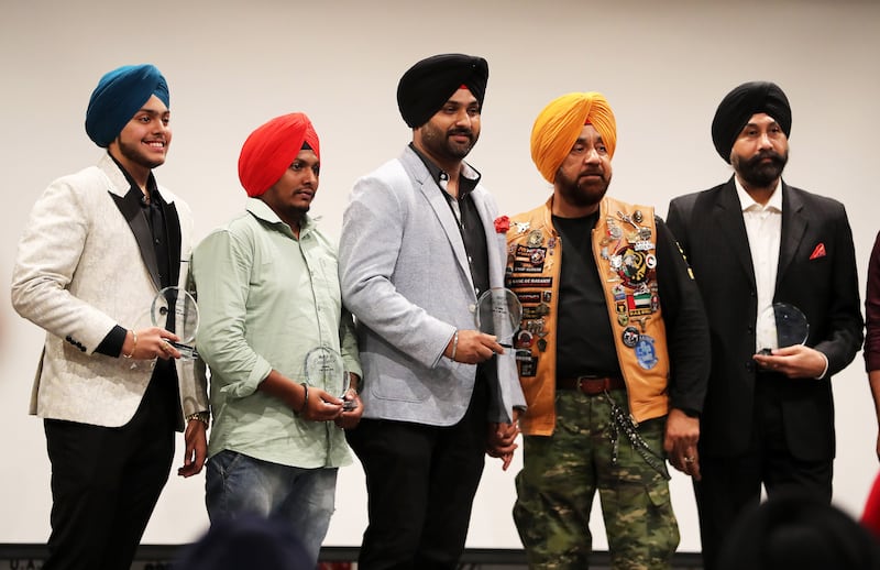 Gurnam Singh, founder of Singhs Motorcycle Club UAE, second from right, honouring Amandeep Singh, founder of Bhangra Crew Dubai, centre, and other members of the school.