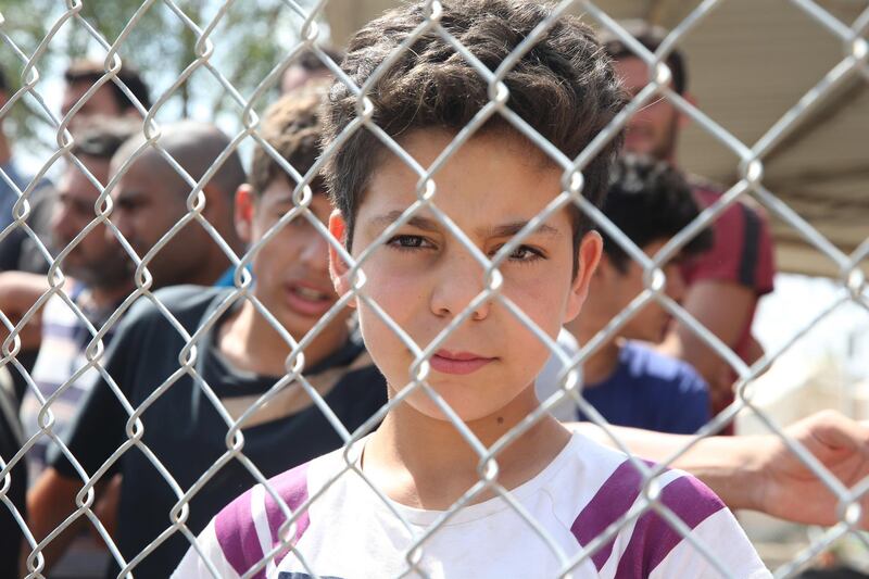 epa08504290 A refugee boy from Syria looks through a fence from inside the Pournara refugee camp in the village of Kokkinotrimithia, Cyprus,23 June 2020. Cypriot authorities reported that no cases of the coronavirus Covid-19 disease have been recorded in the accommodation centre.  EPA/KATIA CHRISTODOULOU