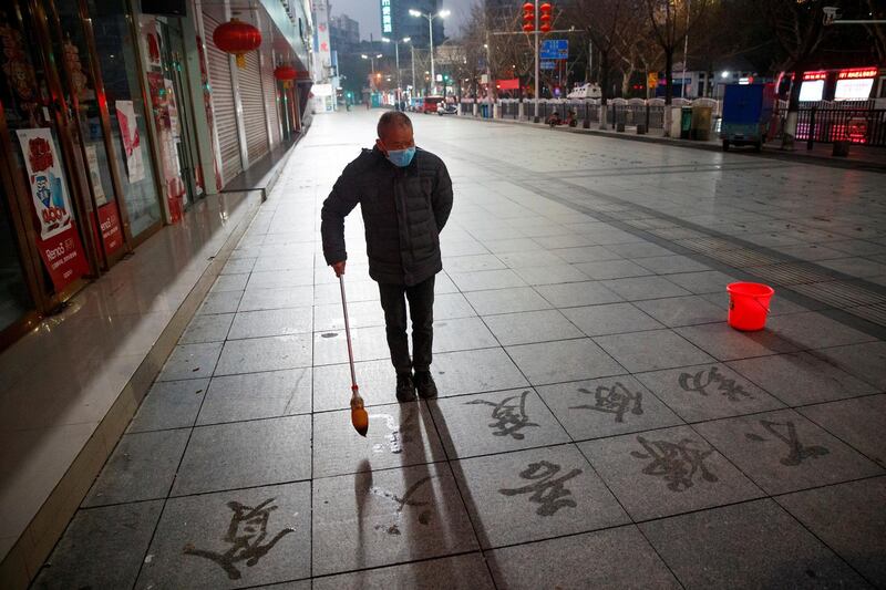 A man wears a face mask as he practices calligraphy of Chinese characters on a pavement as the country is hit by an outbreak of the novel coronavirus in Jiujiang, Jiangxi province, China, February 3, 2020.  REUTERS/Thomas Peter     TPX IMAGES OF THE DAY