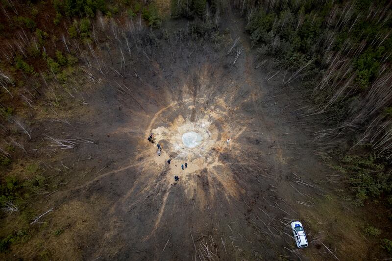 People stand around a crater created by a Russian missile strike, in the village of Buda-Babynetska, near Kyiv, Ukraine. Reuters