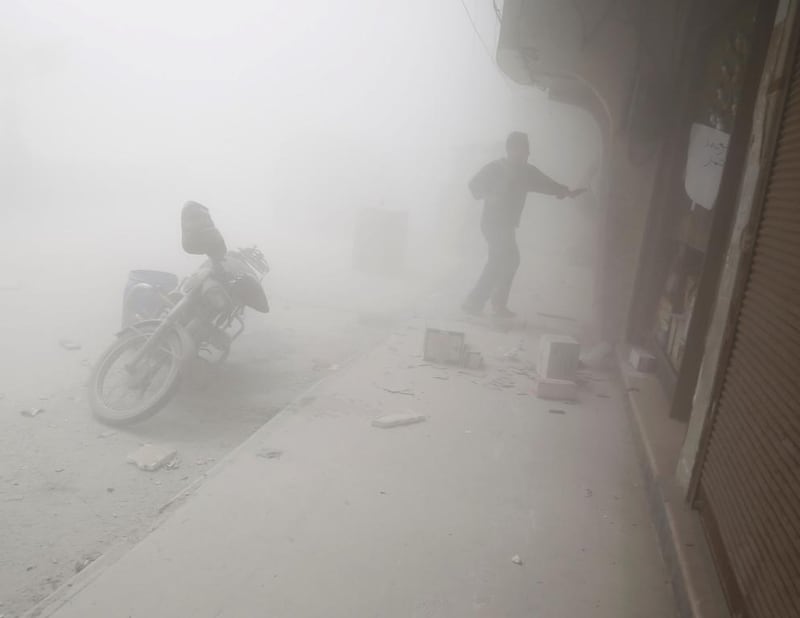A Syrian man runs for cover amid dust and smoke following a reported government air strike on the rebel-controlled town of Hamouria, in the eastern Ghouta region on the outskirts of Damascus, on April 3, 2017. Abdulmonam Eassa / AFP

