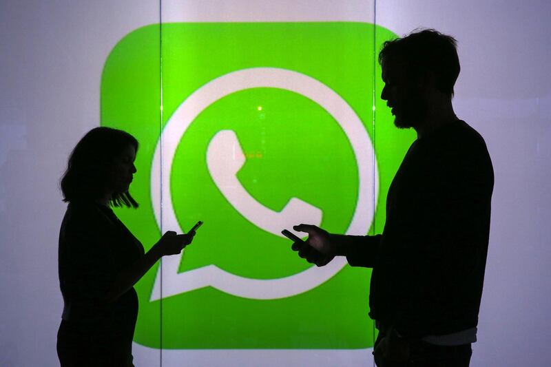 People are seen as silhouettes as they check mobile devices whilst standing against an illuminated wall bearing WhatsApp Inc's logo in this arranged photograph in London, U.K., on Tuesday, Jan. 5, 2016. WhatsApp Inc. offers a cross-platform mobile messaging application that allows users to exchange messages. Photographer: Chris Ratcliffe/Bloomberg