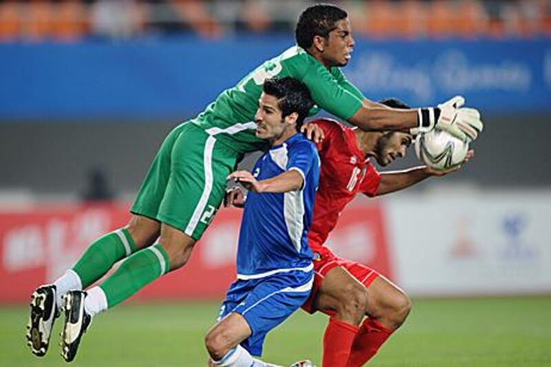 UAE’s Ahmed Mahmoud Juma, in green, catches the ball as his teammate Saeed Salem al Kathiri, in red, vies with Abdullah Abdullah, of Kuwait, in the Asian Games last-16 game in Guangzhou.