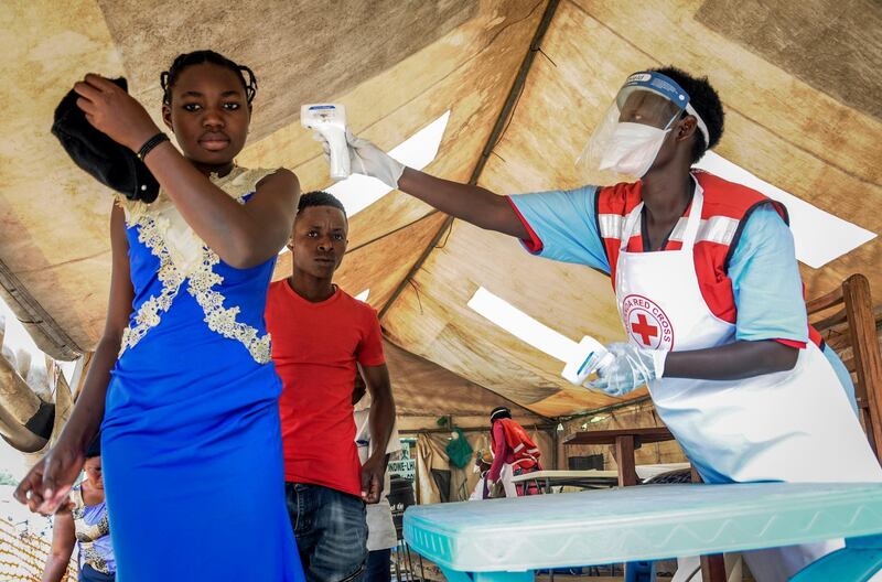 People coming from Congo have their temperature measured to screen for symptoms of Ebola, at the Mpondwe border crossing with Congo, in western Uganda Friday, June 14, 2019. In Uganda, health workers had long prepared in case the Ebola virus got past the screening conducted at border posts with Congo and earlier this week it did, when a family exposed to Ebola while visiting Congo returned home on an unguarded footpath. (AP Photo/Ronald Kabuubi)