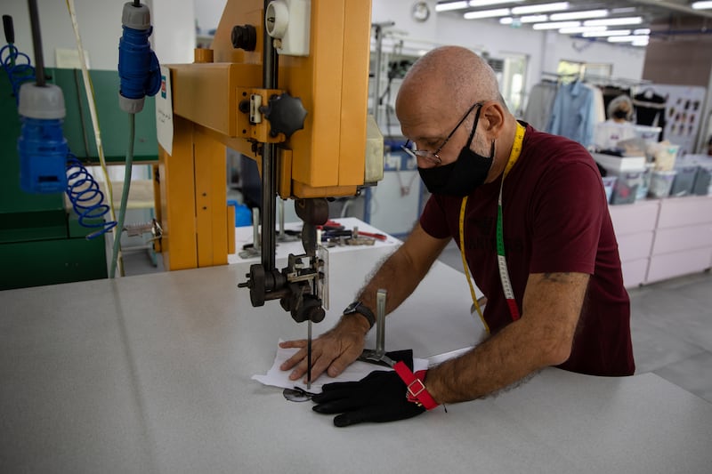 A technician cuts out stencils for silk gloves.