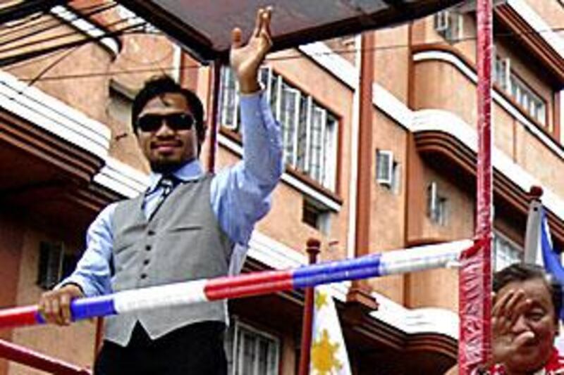 Manny Pacquiao waves to his fans during a victory motorcade in Manila yesterday.