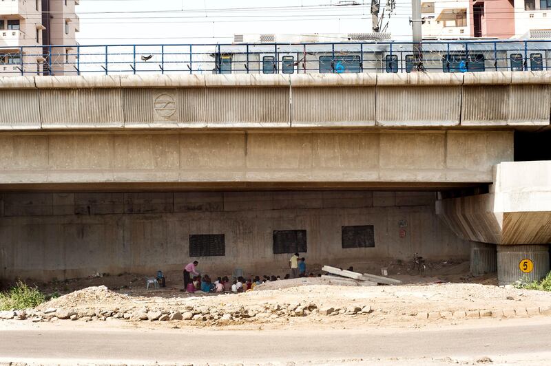 8th April 2013, Shakarpur, New Delhi, India.  A Metro train passes over children studying at a makeshift school under a metro bridge near the Yamuna Bank Metro station in Shakarpur, New Delhi, India on the 8th April 2013. 

Rajesh Kumar Sharma (40), started this makeshift school a year ago. Five days a week, he takes out two hours to teach when his younger brother replaces him at his general store in Shakarpur. His students are children of labourers, rickshaw-pullers and farm workers. This is the 3rd site he has used to teach under privileged children in the city, he began in 1997 fifteen years ago. 

PHOTOGRAPH BY AND COPYRIGHT OF SIMON DE TREY-WHITE

+ 91 98103 99809
+ 91 11 435 06980
+44 07966 405896
+44 1963 220 745
email: simon@simondetreywhite.com