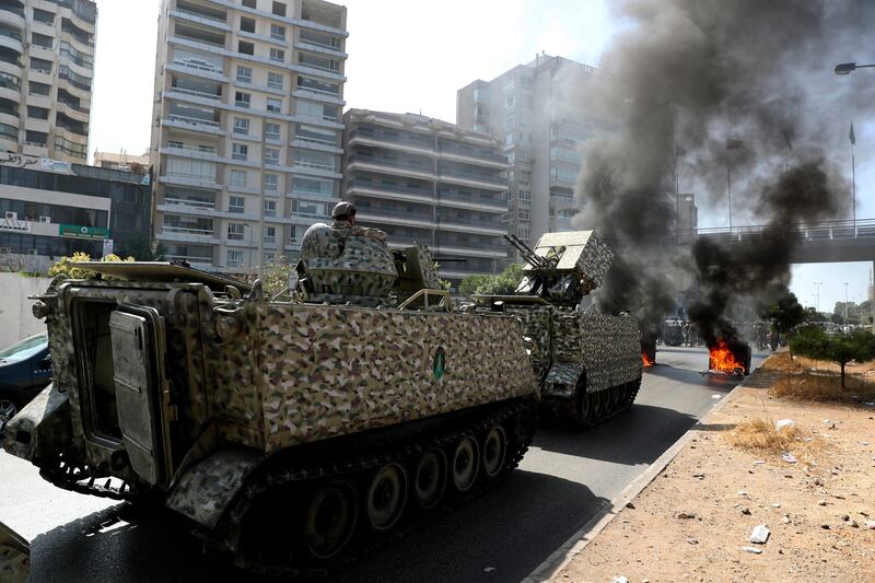 Lebanese soldiers stand guard as supporters of the Shiite Hezbollah and Amal groups burn rubbish containers to block a road during a protest in Beirut.  AP