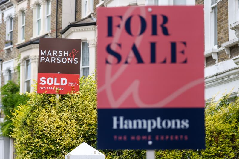 Estate agent signs outside residential properties in London. House price growth in the UK is expected to cool. Bloomberg