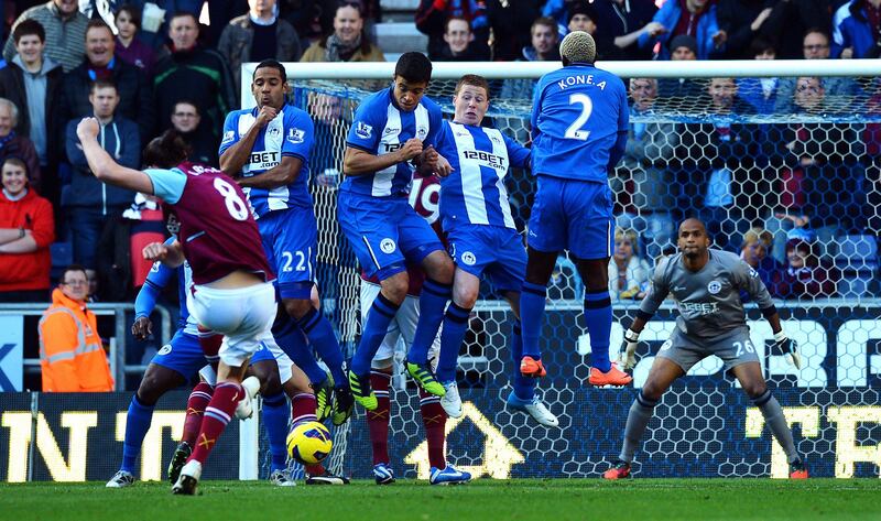 Wigan Athletic players defend a free kick taken by West Ham United's English striker Andy Carroll (L) during the English Premier League football match between Wigan Athletic and West Ham United at The DW Stadium in Wigan, north-west England on October 27, 2012. AFP PHOTO/PAUL ELLIS

RESTRICTED TO EDITORIAL USE. No use with unauthorized audio, video, data, fixture lists, club/league logos or “live” services. Online in-match use limited to 45 images, no video emulation. No use in betting, games or single club/league/player publications
 *** Local Caption ***  765050-01-08.jpg