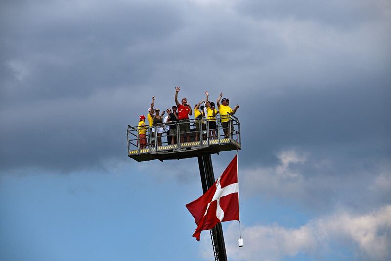 Spectators cheer from on top of a cherry picker adorned with a Danish flag. AFP