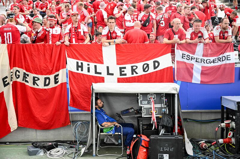 A TV technician sits near Denmark fans, before the Uefa Euro 2024 Group C football match between Denmark and England, in Frankfurt. AFP