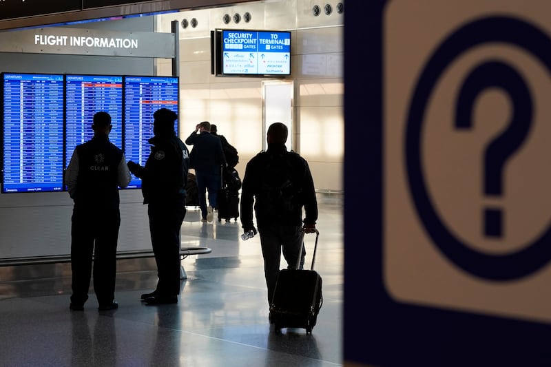 People look at a video display showing flight delays and cancellations at Ronald Reagan Airport. AP