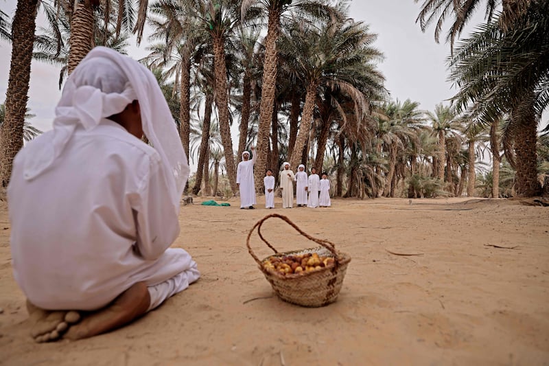An Emirati boy waits by a basket filled with freshly picked dates.