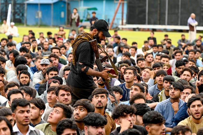 An Afghan security guard walks past fans watching a live broadcast at the Kabul International cricket stadium. AFP