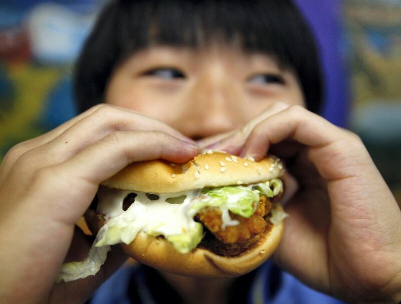 A boy poses with a chicken burger at a fast food outlet in Taipei January 29, 2010. The Taiwan Department of Health on Thursday proposed a ban on junk food advertisements aired around children's television programmes, to tackle the growing child obesity rate, said officials.    REUTERS/Nicky Loh (TAIWAN - Tags: SOCIETY FOOD HEALTH MEDIA) - GM1E61T0YU301