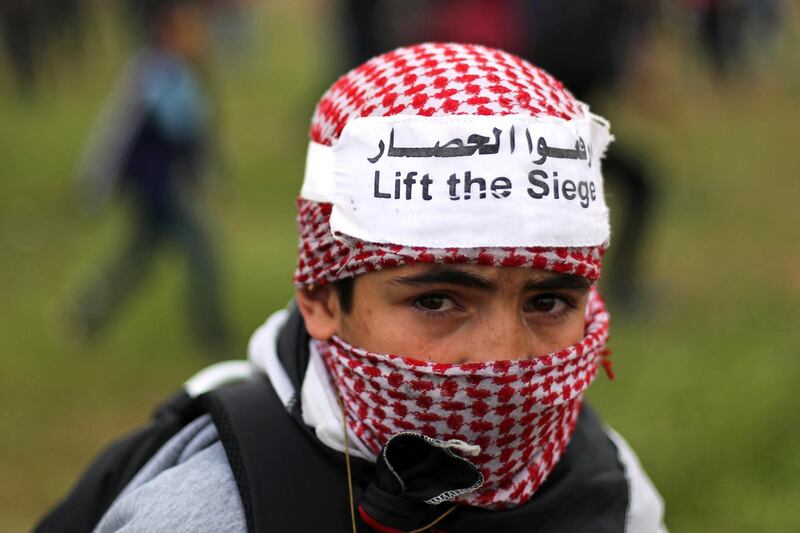 A masked boy reacts to tear gas fired by Israeli forces. Reuters