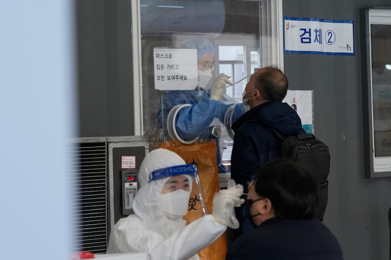 Medical workers take nasal samples from people at a makeshift coronavirus testing site in Seoul, South Korea. AP