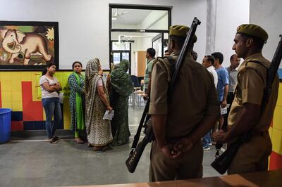 Security personnel stand guard as people line up to vote at a polling station during India's general election in Ghaziabad, Uttar Pradesh on April 11, 2019. India's mammoth six-week general election kicked off April 11, with polling stations in the country's northeast among the first to open. / AFP / PRAKASH SINGH
