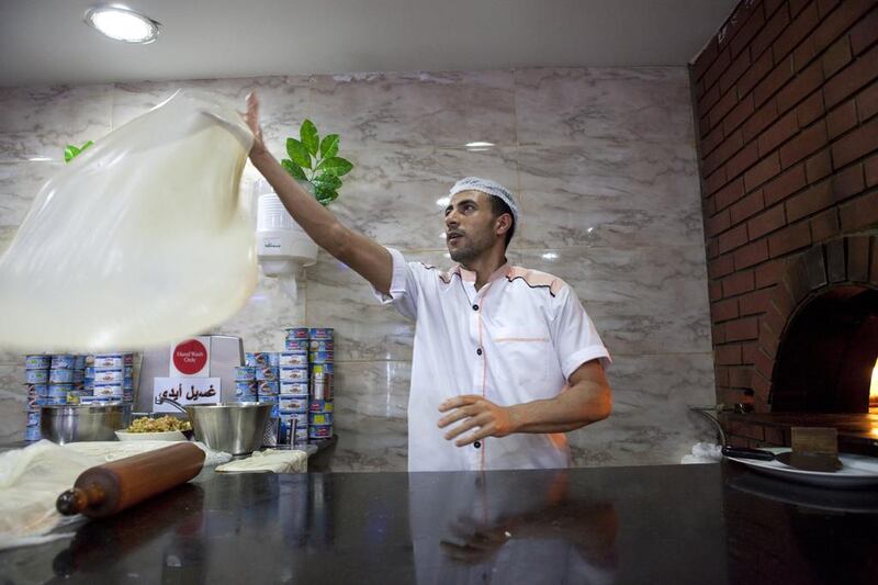 Ismail Fikree, from Egypt flips a roll of fresh dough atAlammor Egyptian restaurant in Karama. Razan Alzayani / The National 