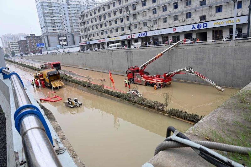 Rescuers use a pumping machine to clear out water from a flooded underpass.