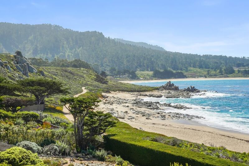 The property looks out over a stretch of beach and verdant forest.