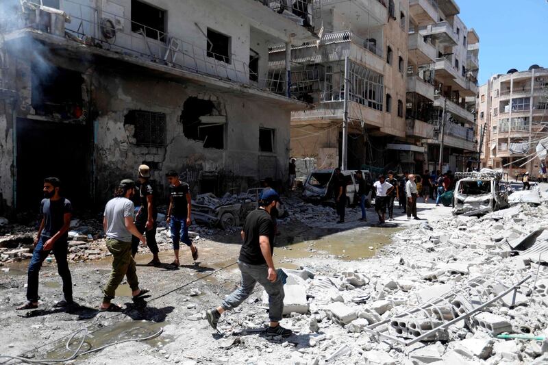 People gather at the site of a reported air strike on the town of Ariha, in the south of Syria's Idlib province on July 28, 2019. / AFP / Omar HAJ KADOUR
