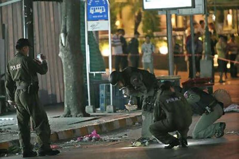 Thai bomb squad experts inspect the site of a bomb blast in front of a convenience store on Ratchadamri Road, Bangkok.