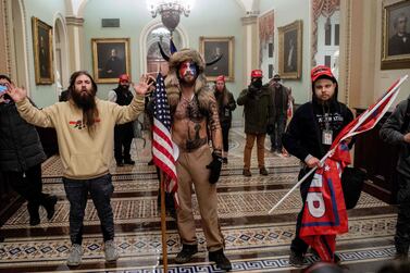 (FILES) In this file photo taken on January 6, 2021, Supporters of US President Donald Trump, including Jake Angeli (C), a QAnon supporter known for his painted face and horned hat, enter the US Capitol on January 6, 2021, in Washington, DC.  - A conspiracy theorist who became one of the most recognized rioters storming the US Capitol last January pleaded guilty on September 3, 2021 to obstructing congressional proceedings, a charge carrying a prison sentence of up to 20 years.  (Photo by SAUL LOEB  /  AFP)