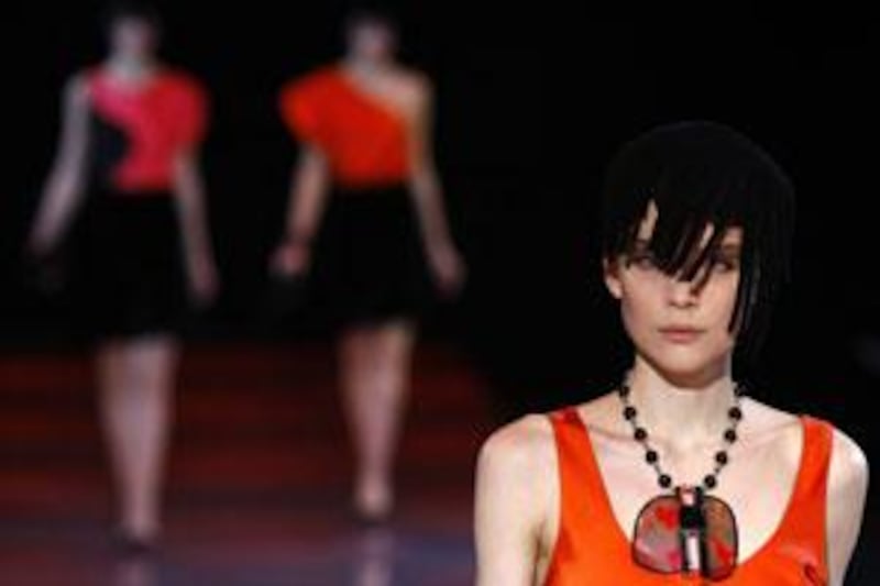 In the Giorgio Armani collection, bright spots of red and orange highlighted black dresses.