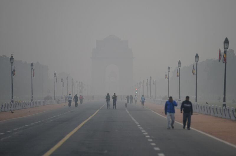 People walk early in the morning as smog covers India Gate war memorial in New Delhi on November 6, 2017.
Delhi, one of the world's most polluted cities, suffers from high levels of pollution during winter months, with millions of vehicles contributing to the city's bad air.  / AFP PHOTO / SAJJAD HUSSAIN