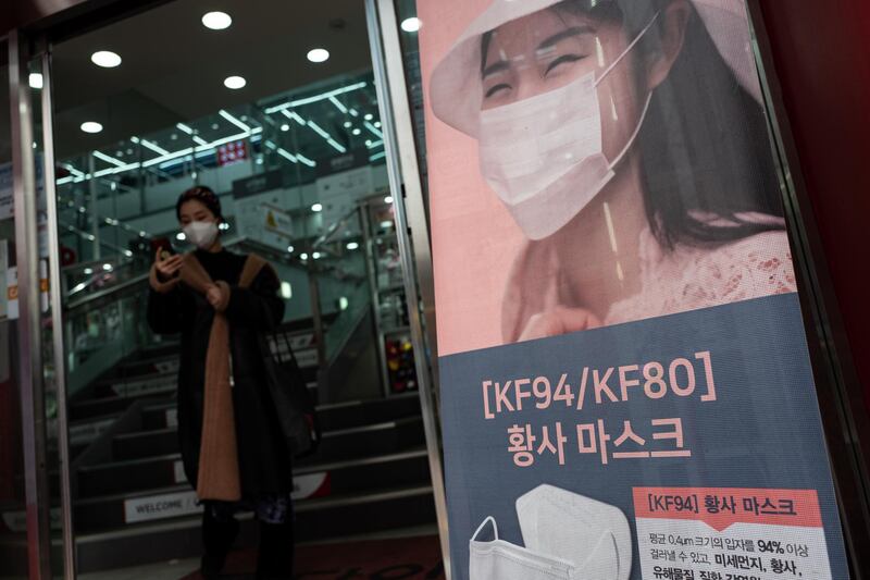 A South Korean woman, left, wearing a mask exits a store in central Seoul.  EPA
