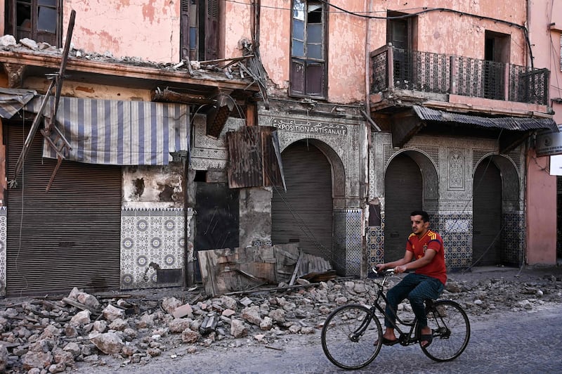 A man rides a bicycle past an earthquake-damaged building in the old quarters of Marrakesh. AFP