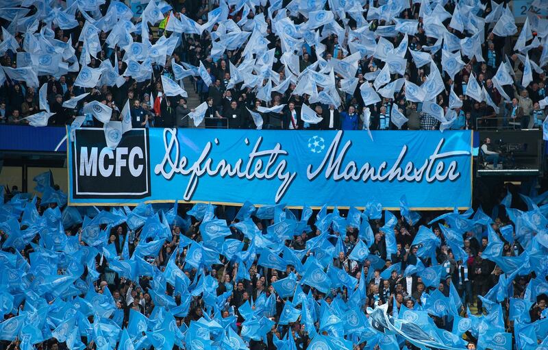 MANCHESTER, ENGLAND - APRIL 17: Manchester City fans wave flags and a banner saying Definitely Manchester in similar style to the Oasis album Definitely Maybe before the UEFA Champions League Quarter Final second leg match between Manchester City and Tottenham Hotspur at at Etihad Stadium on April 17, 2019 in Manchester, England. (Photo by Visionhaus/Getty Images)