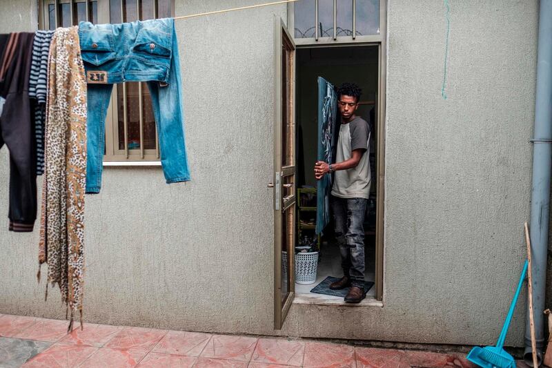 Eritrean artist Nebay Abraha, 23, exits his room and studio carrying a painting in Addis Ababa. AFP