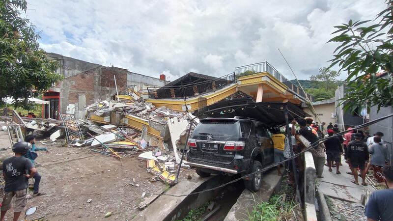 Rescuers search for survivors at a collapsed building in Mamuju city. AFP