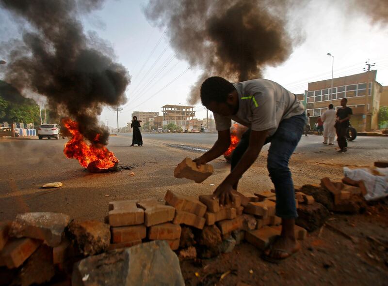 A Sudanese protester uses paving stones to block Street 60 as the military forces tried to disperse the sit-in outside Khartoum's army headquarters. AFP
