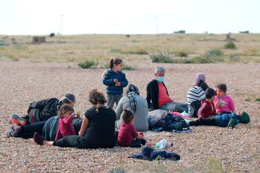 A group of migrants rest on the beach as they wait for UK Border Force officials at Dungeness, southern England. AP