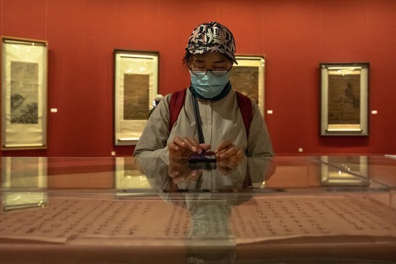 A woman wearing a protective face mask visits the 'A tribute to donors' exhibition at the National Art Museum of China on the first day after reopening.  EPA