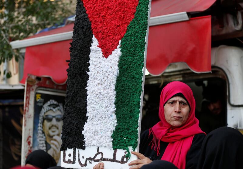 A Palestinian woman holds a symbolic of the Palestine flag with Arabic words that read:"Palestine for us," as she attends a protest against the White House plan for ending the Israeli-Palestinian conflict, at Burj al-Barajneh refugee camp, south of Beirut, Lebanon, Wednesday, Jan. 29, 2020. At refugee camps across the country, Palestinians staged strikes, protests and sit-ins a day after U.S. President Donald trump revealed the long-awaited details of the plan, denouncing it as ridiculously lop-sided and saying it gives them no rights. (AP Photo/Hussein Malla)