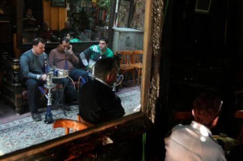 Egyptians and tourists smoke shisha and drink tea in the popular El-Fishawi coffee shop in the tourist bazaar close to the Al-Hussein mosque in Cairo on March 15, 2011. AFP PHOTO/MAHMUD HAMS