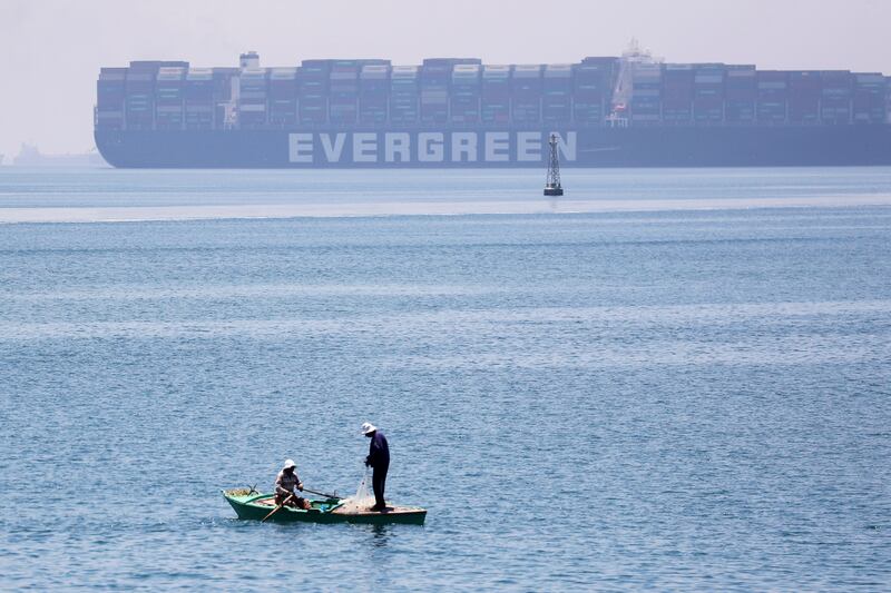 Men fish near the 'Ever Given', which blocked the Suez Canal for six days in March.