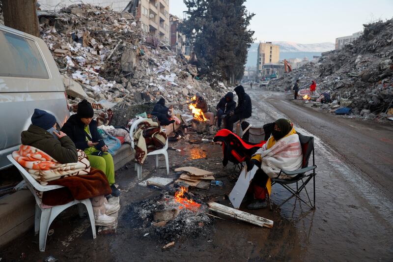 People keep warm by a fire as the search for survivors continues a week after the earthquake in Kahramanmaras, Turkey. Reuters