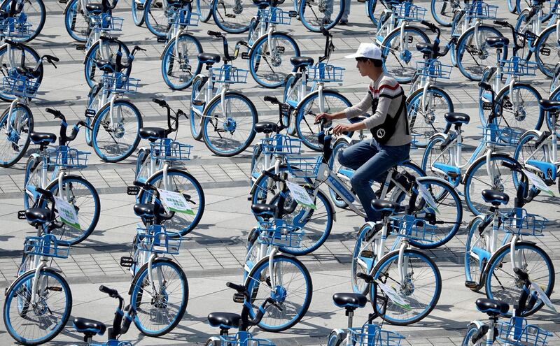 A man rides a bicycle of bike-sharing firm Hellobike amid bicycles placed on a plaza in Zhengzhou, Henan province, China. Reuters